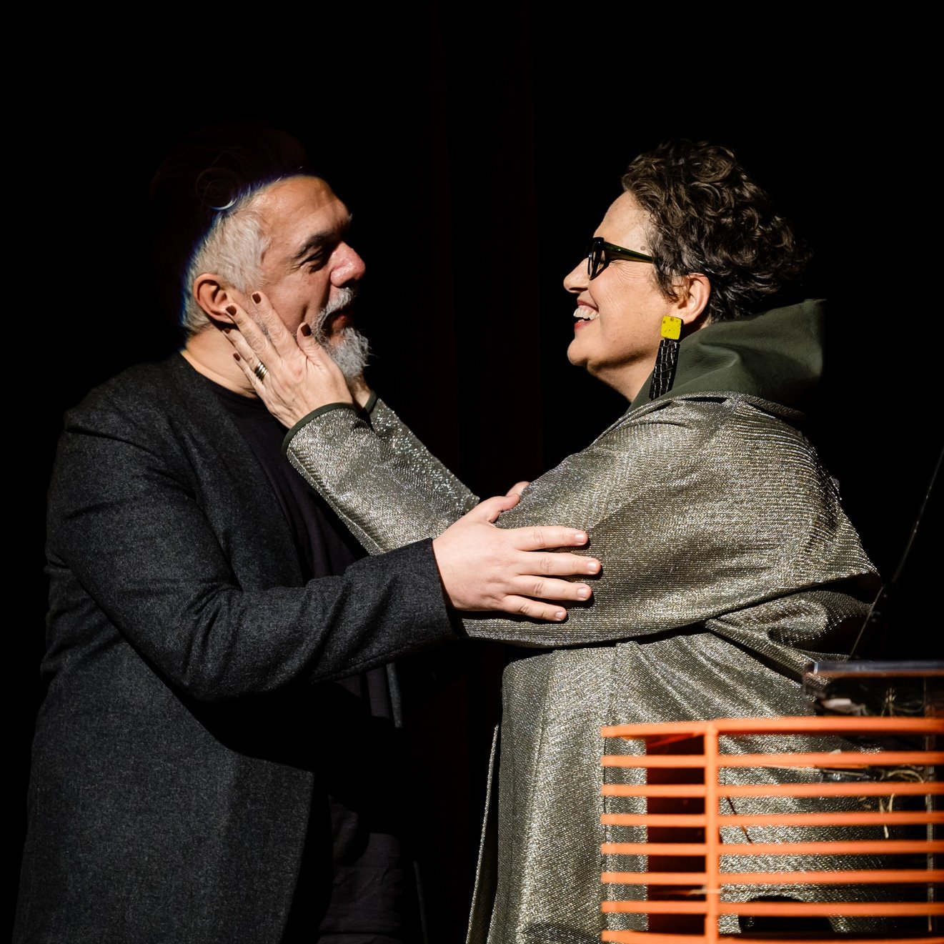 Two presenters sharing an embrace onstage at the Interior Design Hall of Fame gala.